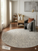 6' Round Ivory & Gray Geometric Textured Washable Area Rug placed in a cozy living room corner with accent chair, floor lamp, and wooden side table.
