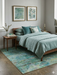 6' x 6' Square Blue Green Distressed Floral Vintage Transitional Area Rug styled in a bedroom with matching blue-green bedding and natural wood furniture.