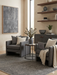 6' x 6' Square Charcoal Gray Textured Minimalist Modern Area Rug placed in a contemporary living room with armchairs, wood shelving, and neutral decor.