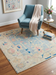 6' x 6' Square Ivory & Blue Tribal Medallion Traditional Area Rug styled in a reading nook with a blue accent chair and side table.