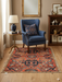 6' x 6' square rust orange & blue floral medallion traditional area rug placed in a cozy reading nook with a blue armchair, side table, and warm neutral decor.
