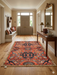 6' x 6' square rust orange & blue floral medallion traditional area rug placed in an entryway with a console table, wall mirror, and bench seating.