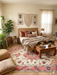 6' x 9' Rectangular Cream & Pink Floral Oriental Traditional Area Rug styled in a cozy bedroom with warm wood tones and bohemian accents.