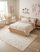 6' x 9' Rectangular Ivory & Blush Abstract Minimalist Modern Area Rug styled in a bedroom with light wood furniture and neutral bedding.