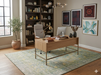 6' x 9' Rectangular Mint Green Distressed Medallion Traditional Washable Area Rug shown beneath a wooden desk in a modern home office with built-in shelving and botanical décor.