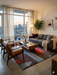 6' x 9' Rectangular Multicolor Red Blue & Charcoal Abstract Geometric Modern Area Rug styled in a living room with a sofa, accent chairs, and large window views.