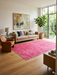 6' x 9' Rectangular Pink & Rose Distressed Vintage Washable Area Rug styled in a living room with warm-toned decor and abstract wall art.