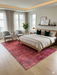 6' x 9' Rectangular Red & Pink Distressed Abstract Modern Area Rug styled in a bedroom with neutral bedding and modern decor.