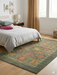 6' x 9' rectangular olive green & multicolor floral medallion traditional area rug styled in a bedroom with a light upholstered bed, soft linens, and warm natural light.