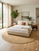 7' Round Beige & Natural Solid Textured Jute-Style Area Rug styled in a bedroom with neutral bedding and minimalist decor.