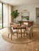 7' Round Beige & Natural Solid Textured Jute-Style Area Rug styled in a dining area with a round table and soft natural light.