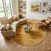 7' Round Gold & Beige Distressed Abstract Modern Area Rug placed in a bright contemporary living room beneath a glass coffee table.