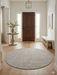 7' round ivory gray micro dot textured modern area rug placed in an entryway with a wooden front door, console table, and minimal decor.