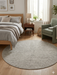 7' round ivory gray micro dot textured modern area rug styled in a bedroom with a wooden bed, soft linens, and natural light from a window.