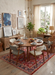 7' x 10' Rectangle Red & Navy Floral Traditional Washable Area Rug styled in a warm dining room with a round wooden table, upholstered chairs, and layered wall art.