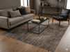 7' x 7' Square Taupe Gray Distressed Medallion Vintage Area Rug styled in a sophisticated living room with a neutral sofa, black leather accent chair, and modern metal coffee table.