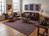 7' x 9' Rectangular Charcoal Rust Geometric Tribal Traditional Washable Area Rug styled in a sophisticated living room with deep burgundy seating, warm wood accents, and modern artwork.