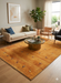 7' x 9' Rectangular Gold Camel Animal Tribal Southwestern Area Rug styled in a living room with a sofa, accent chair, and modern decor.