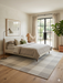 7' x 9' Rectangular Ivory & Gray Checkered Plaid Modern Farmhouse Area Rug placed in a bright bedroom with a neutral upholstered bed, wood flooring, and soft natural light.
