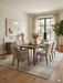 7' x 9' Rectangular Ivory & Gray Checkered Plaid Modern Farmhouse Area Rug placed in a dining room with a wooden table, upholstered chairs, and minimalist decor.