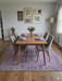 7' x 9' Rectangular Ivory & Purple Floral Medallion Traditional Area Rug showcased beneath a mid-century dining table with upholstered gray chairs.