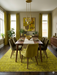 7' x 9' Rectangular Mustard Gold & Brown Distressed Medallion Traditional Washable Area Rug placed in a mid-century modern dining room beneath a wooden dining table.