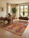 7' x 9' Rectangular Orange Multi Color Geometric Tribal Southwestern Area Rug styled in a home office with a wooden desk and shelving.