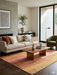 7' x 9' Rectangular Pink Orange Abstract Geometric Modern Area Rug styled in a living room with neutral seating and warm wood accents.