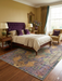 7' x 9' Rectangular Purple & Multicolor Medallion Distressed Traditional Area Rug styled in a classic bedroom with wooden bed and warm décor.