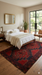 7' x 9' Rectangular Red & Black Tribal Geometric Traditional Area Rug placed in a bright contemporary bedroom with large window and wood floors.