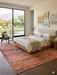 7' x 9' Rectangular Rust Terracotta Distressed Abstract Vintage Area Rug styled in a bedroom with neutral tones and natural light.
