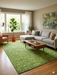 7' x 9' rectangular green textured micro dot modern area rug placed in a bright living room with a neutral sofa, wood coffee table, and large window.