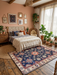 7' x 9' rectangular navy blue & red floral medallion traditional area rug styled in a cozy bedroom with layered textiles, natural decor, and soft daylight.