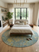 8' Round Blue & Gold Distressed Floral Traditional Washable Area Rug styled in a bedroom with a platform bed, neutral bedding, and wood flooring.