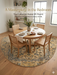 8' Round Ivory & Blue Floral Medallion Traditional Area Rug placed in a dining area with a round table, wood chairs, and minimalist decor.