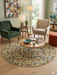 8' round multicolor geometric triangle pattern modern area rug placed in a cozy living room with armchairs and a round coffee table.