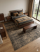 8' x 10' Rectangular Brown & Beige Distressed Abstract Modern Washable Area Rug styled in a bedroom with a bed and wood furniture.