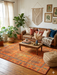 8' x 10' Rectangular Orange & Green Tree Motif Traditional Vintage Washable Area Rug styled in a warm bohemian living room.