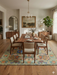 8' x 10' Rectangular Sage Green Multicolor Floral Traditional Washable Area Rug styled in a bedroom with warm wood furniture, layered bedding, and soft neutral tones.