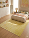8' x 10' Rectangular Yellow Floral Distressed Traditional Area Rug displayed in a bedroom beneath a bed with soft yellow and neutral bedding accents.