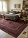 8' x 10' rectangular burgundy & black distressed geometric traditional area rug styled in a bedroom with a wood bed frame, layered bedding, and soft natural light.