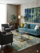 8' x 12' Rectangular Blue & Green Distressed Floral Vintage Washable Area Rug placed in a contemporary living room beneath a glass coffee table.