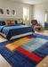 8' x 12' Rectangular Blue & Multicolor Abstract Modern Area Rug placed in a modern bedroom beneath a bed with coordinated blue bedding.