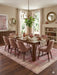 8' x 12' Rectangular Pink & Ivory Distressed Oriental Vintage Area Rug showcased beneath a wooden dining table with blush upholstered chairs.