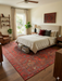 8' x 12' Rectangular Red & Black Tribal Geometric Traditional Area Rug styled in a bedroom with a wooden bed frame and neutral bedding.