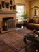 8' x 12' rectangular brown & tan animal print leopard pattern modern area rug styled in a living room with a fireplace, leather sofa, and natural accents.