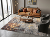 8' x 8' Square Gray Gold Abstract Modern Washable Area Rug styled in a contemporary living room with a tan leather sofa, gray accent chairs, and a round wood and glass coffee table.