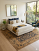 8' x 8' square gold & black floral medallion traditional area rug styled in a bedroom with a light upholstered bed, soft bedding, and natural light.